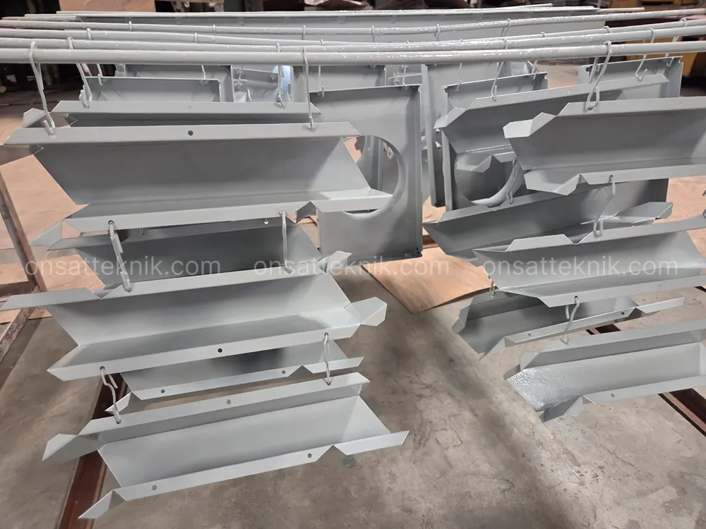 Komponen bracket besi digantung di conveyor saat proses powder coating warna abu-abu
